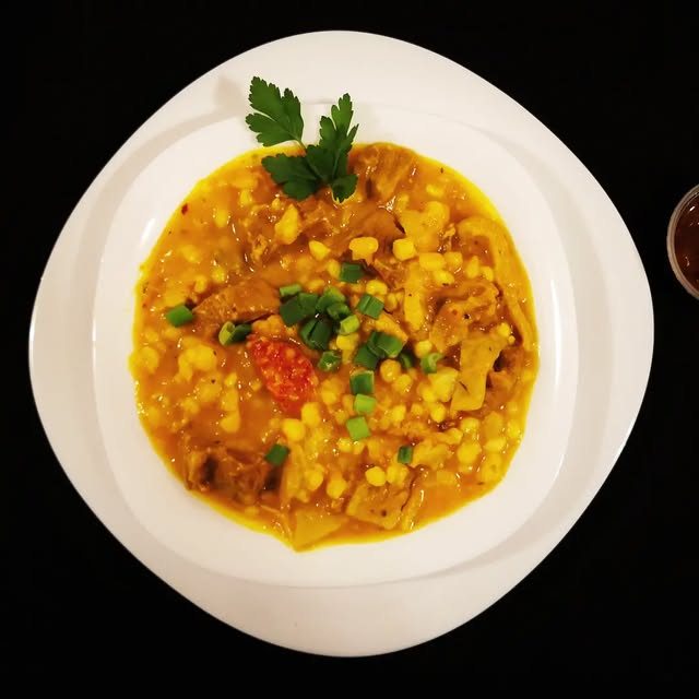 Plato de locro con cebolla de verdeo y ají picante, visto desde arriba
